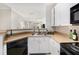 Kitchen with stainless sink, white cabinets, black appliances, and view of the living room at 4221 W Spruce St # 2104, Tampa, FL 33607
