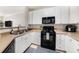 Well-lit kitchen with white cabinets, black appliances, and neutral countertops and backsplash at 4221 W Spruce St # 2104, Tampa, FL 33607