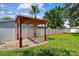 Landscaped backyard features a red pergola with stone groundcover and manicured lawn at 4400 Helena Ne St, St Petersburg, FL 33703