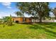 Wide view of a backyard with a covered patio, mature trees, and lush lawn at 4400 Helena Ne St, St Petersburg, FL 33703