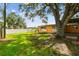 Wide view of backyard featuring a mature shade tree, green lawn, and covered patio at 4400 Helena Ne St, St Petersburg, FL 33703