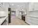 Modern kitchen featuring white cabinets, stainless steel appliances, and terrazzo flooring, open to the living area at 4400 Helena Ne St, St Petersburg, FL 33703