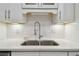 Close-up of the kitchen sink featuring white cabinets, stainless steel faucet, and white countertop at 4400 Helena Ne St, St Petersburg, FL 33703