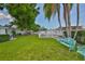 Expansive backyard featuring a well-manicured lawn, mature trees, white fencing, and decorative seating area at 513 Fairhope Dr, Apollo Beach, FL 33572
