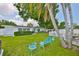 Lush backyard with a green lawn, mature trees, white fencing, and a charming seating area, creating a tranquil retreat at 513 Fairhope Dr, Apollo Beach, FL 33572