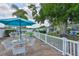 Relaxing patio with table, seating, umbrella, with lush green lawn, complemented with manicured garden, and white fence at 513 Fairhope Dr, Apollo Beach, FL 33572