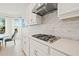 Gourmet kitchen with a stone tile backsplash, white cabinets, stainless steel hood vent, and a gas cooktop at 5810 Fieldmoor Ct, Palmetto, FL 34221