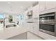 Bright kitchen with white cabinets, stainless steel appliances including built-in oven, and a sink with a bay window view at 5810 Fieldmoor Ct, Palmetto, FL 34221