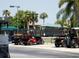 Several golf carts parked at an angle on a lot, with mature palm trees and a partially visible building at 6715 Grand Estuary Trl # 203, Bradenton, FL 34212