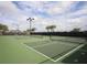 Community pickleball court with a dark fence, overhead lighting, and mature palm trees in the background at 6715 Grand Estuary Trl # 203, Bradenton, FL 34212