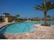 Relaxing community pool with palm trees and a building with lounge chairs under a clear blue sky at 6715 Grand Estuary Trl # 203, Bradenton, FL 34212