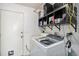 Functional laundry area with modern washer and dryer, shelving, and an exterior door at 7330 Fairwood Ave, New Port Richey, FL 34653