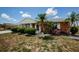 Charming brick home showcasing a lovely front yard with manicured landscaping and palm trees at 801 Oakmont Ave, Sun City Center, FL 33573