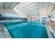 Large, indoor pool with bright blue water, ample seating, and a tall, vaulted ceiling for comfortable swimming at 801 Oakmont Ave, Sun City Center, FL 33573