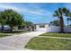 Charming single-story home featuring a well-manicured lawn, painted driveway, and tropical landscaping at 9097 Southern Comfort Dr, Largo, FL 33773