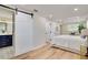Bright main bedroom featuring wood floors, neutral walls, and a sliding barn door to the ensuite bathroom at 9097 Southern Comfort Dr, Largo, FL 33773