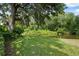 Lush backyard with mature trees, and a view of a pond at 9307 Golf View Dr, New Port Richey, FL 34655