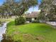 Well-maintained backyard with a lush green lawn, mature trees, and a peaceful pond view at 9307 Golf View Dr, New Port Richey, FL 34655