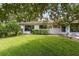 Exterior view of a well-maintained backyard with lush green grass, mature trees and a patio at 9307 Golf View Dr, New Port Richey, FL 34655