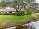 Beautiful home exterior with mature trees, lush landscaping, and serene pond backdrop at 9307 Golf View Dr, New Port Richey, FL 34655