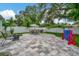 Spacious backyard featuring a stone patio, green lawn, mature trees, and outdoor seating area at 10664 Starkey Rd, Seminole, FL 33777