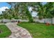 Spacious backyard featuring a stone patio, green lawn, mature trees, and outdoor seating area at 10664 Starkey Rd, Seminole, FL 33777