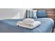 A close-up of a twin bed with a stack of white towels on top of a blue quilt at 10664 Starkey Rd, Seminole, FL 33777