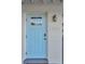 Close-up of a charming light blue front door with decorative window, house number, and exterior light fixture at 10664 Starkey Rd, Seminole, FL 33777