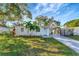 Charming single-story home with a well-manicured lawn and inviting blue front door, complemented by lush palm trees at 10664 Starkey Rd, Seminole, FL 33777