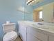 Bright bathroom with a large mirror, white vanity, and a toilet at 12701 N 57Th St, Tampa, FL 33617