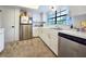 Well-lit kitchen featuring white cabinets, stainless steel appliances, and a window overlooking the yard at 12701 N 57Th St, Tampa, FL 33617