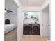 Functional laundry room with modern washer and dryer units and shelving for storage at 12701 N 57Th St, Tampa, FL 33617