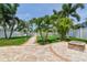 Beautifully landscaped backyard featuring a brick pathway, lush lawn, palm trees, and a fire pit at 13118 Rain Lily Dr, Riverview, FL 33579