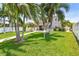 Lush green backyard featuring a covered patio, mature palm trees, and manicured lawn at 13118 Rain Lily Dr, Riverview, FL 33579