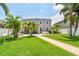 Beautifully landscaped backyard featuring a brick pathway, lush lawn, palm trees, and a covered patio with outdoor seating at 13118 Rain Lily Dr, Riverview, FL 33579