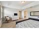 A well-lit bedroom featuring wood-look flooring, dresser, wicker chair, and a tray ceiling at 13118 Rain Lily Dr, Riverview, FL 33579