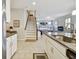 Open floorplan featuring a kitchen island, white cabinets, granite counters, and view of the staircase and living area at 13118 Rain Lily Dr, Riverview, FL 33579
