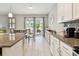 Open kitchen and dining area with granite counters, stainless appliances, tile floors, and sliding glass doors to the lanai at 13118 Rain Lily Dr, Riverview, FL 33579