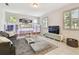 Cozy living room featuring a modern sectional sofa, decorative shelving with lights, and large windows at 13118 Rain Lily Dr, Riverview, FL 33579
