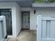 A gray door offers entry to this home, framed by a white textured wall and shadowed by an elegant outdoor light at 1371 Pine Ridge E Cir # B8, Tarpon Springs, FL 34688