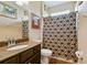 Bathroom with brown granite countertop, dark wood vanity, and tiled shower with patterned curtain at 15135 Azra Dr, Odessa, FL 33556