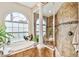 Elegant bathroom featuring a glass enclosed shower, columns, and a large arched window at 15135 Azra Dr, Odessa, FL 33556