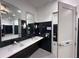 Modern community bathroom with sleek black tiling, dual sinks, and accessible features at 15528 Corona Del Mar Dr, Wimauma, FL 33598