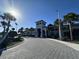 Clubhouse exterior with palm trees, manicured landscaping, and a paved circular driveway under a sunny sky at 15528 Corona Del Mar Dr, Wimauma, FL 33598
