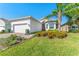 Beautiful single-Gathering home featuring a well-manicured lawn, vibrant flowerbeds, and a brick driveway, enhancing its appeal at 15528 Corona Del Mar Dr, Wimauma, FL 33598
