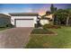 Charming single-story home boasts a brick driveway, two-car garage, and meticulously landscaped front yard at 15528 Corona Del Mar Dr, Wimauma, FL 33598