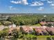 This aerial view captures a neighborhood of tile-roofed homes with a forest as a backdrop at 1617 El Pardo Dr, Trinity, FL 34655