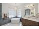 Luxurious bathroom with a freestanding tub, marble-look tile, and a vanity with an illuminated mirror at 1617 El Pardo Dr, Trinity, FL 34655