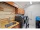 Well-lit laundry room features a modern washer/dryer set and a sink with attractive stone countertops and backsplash at 1617 El Pardo Dr, Trinity, FL 34655
