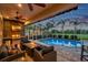 Inviting screened pool area with an outdoor kitchen, a built-in grill, a cozy seating area, and picturesque golf course views at 1617 El Pardo Dr, Trinity, FL 34655
